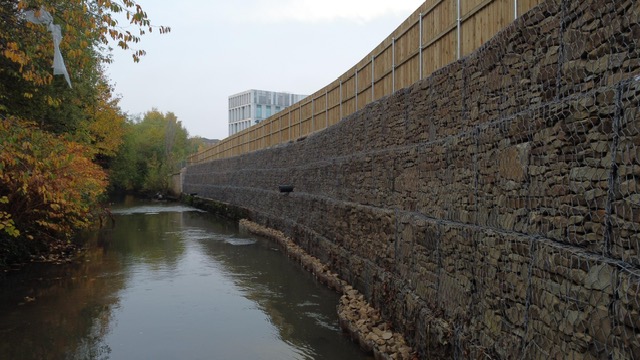 An image of a stone retaining wall by a river bank.
